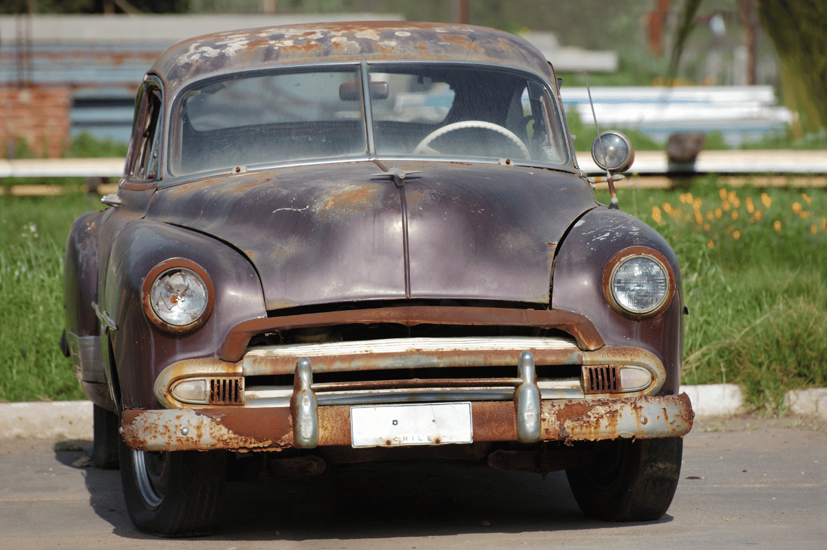 rusty car parked outside house