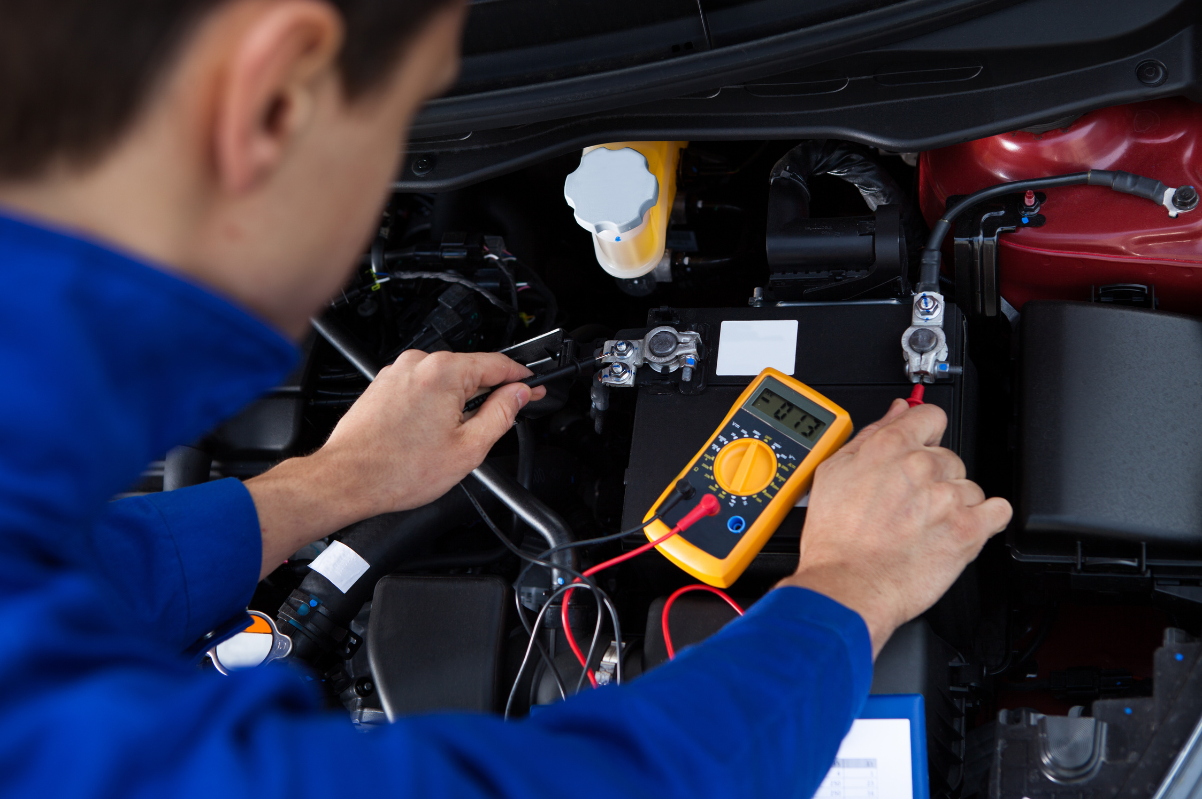 mechanic testing car battery multimeter